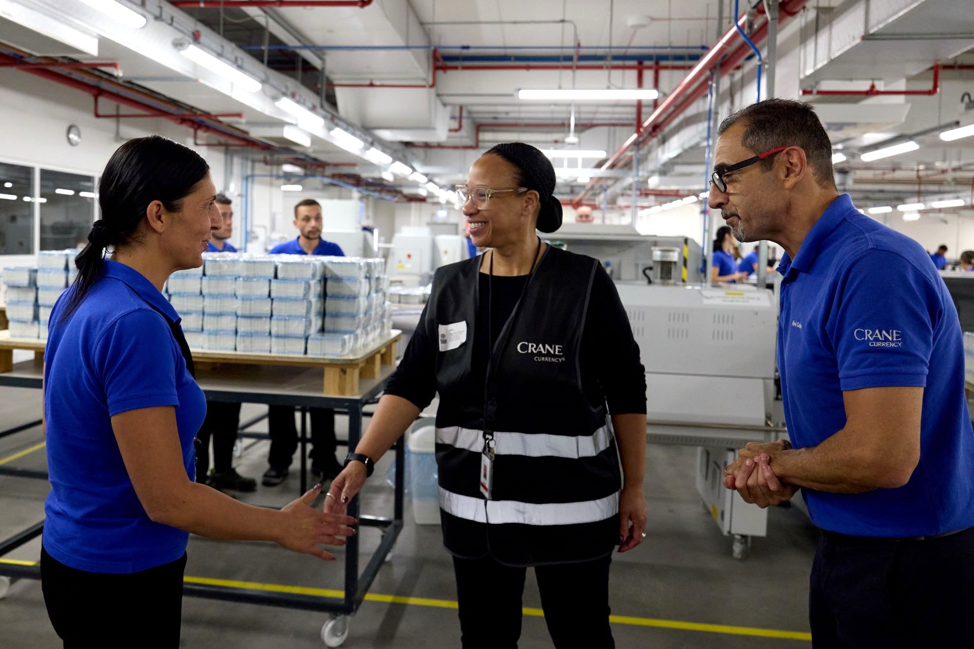 Aleta Richards reaching out to shake the hand of an associate in the finishing department.